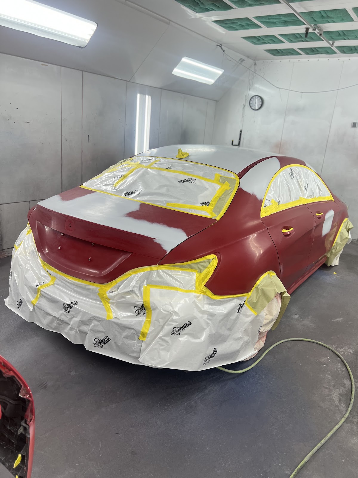 Sedan masked and mid-refinish in the Zuniga paint booth